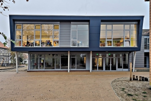 Die Fassade des blauen Schulgebäudes mit Einblick in einige Klassenräume