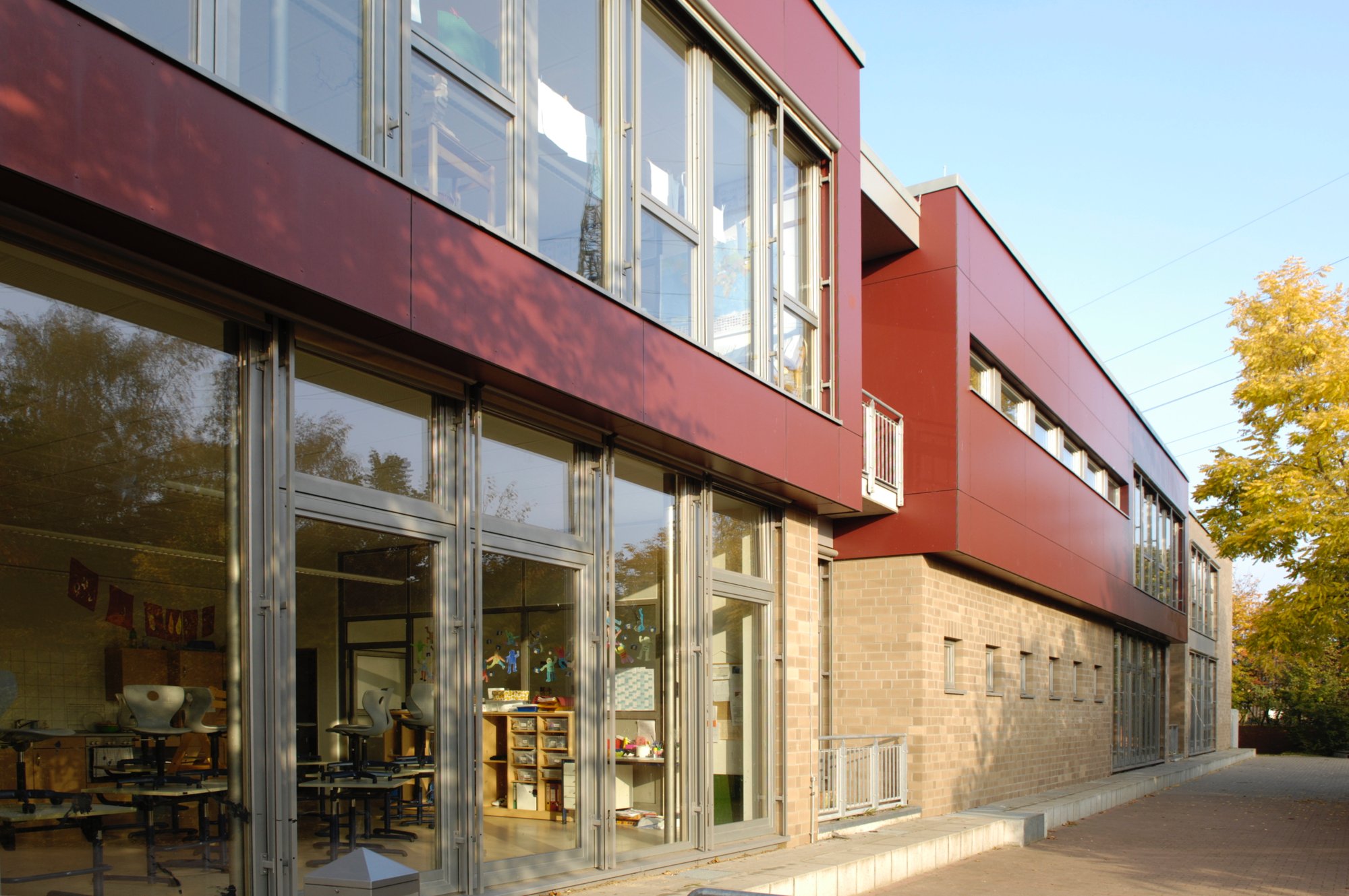 Ein rotes Schulgebäude, schräg fotografiert, mit großen Fenstern